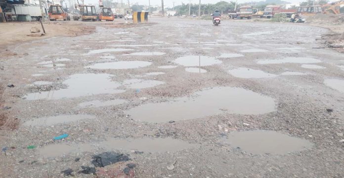 Road filled with potholes can be seen at Shastripuram Junction.